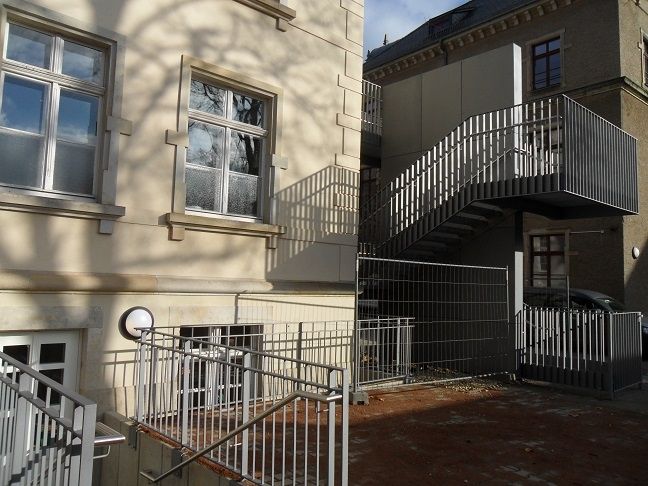 Außenansicht mit Metallgeländern und einer Wendeltreppe an einer Fassade