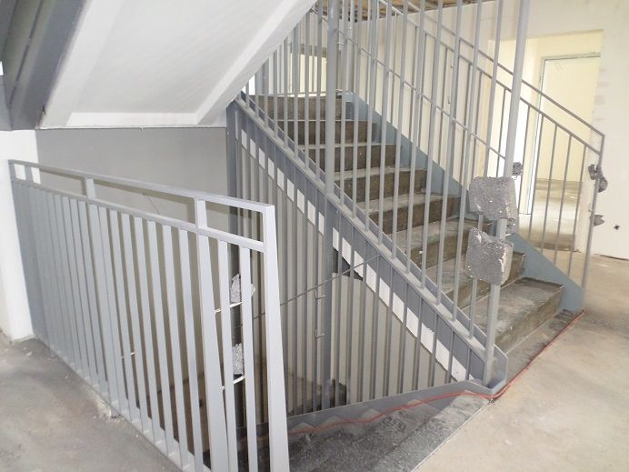 Grauer Metall-Treppenaufgang mit Geländern im Treppenhaus