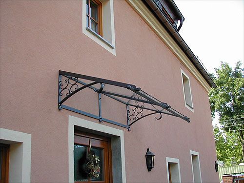 Geschmiedetes Vordach über einer Tür an einer verputzten Hauswand