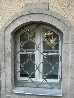 Fenstergitter aus Schmiedeeisen mit Diamant-Muster auf einem Bogenfenster