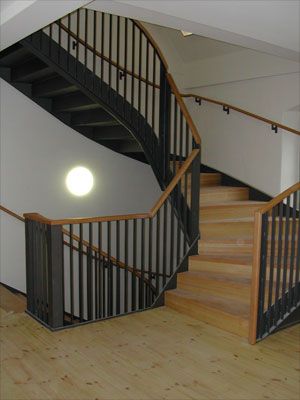 Schmiedeeiserne Wendeltreppe mit Holzgeländer im Treppenhaus