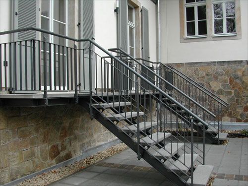Stahl-Treppe mit Geländer an einer Steinmauer