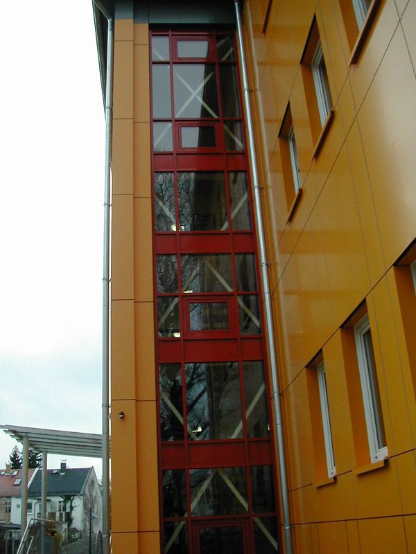 Rot umrandete Stahlglaskonstruktion an einer modernen Fassade