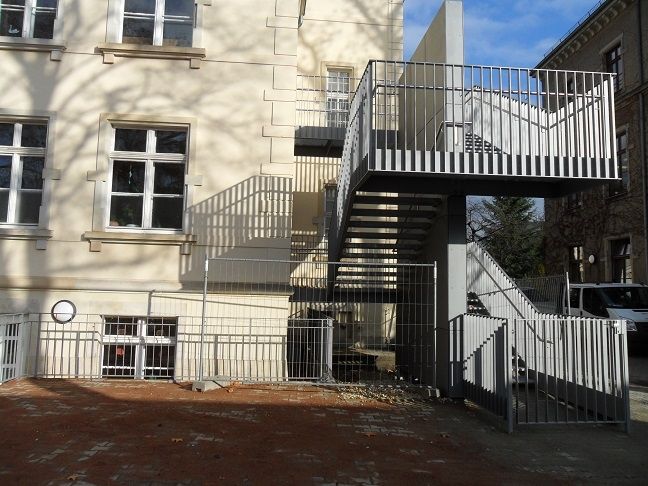 Fertiggestellte externe Metalltreppe mit Geländer an einer Fassade