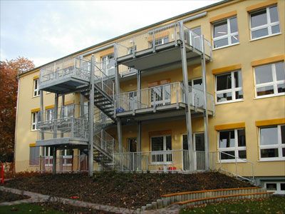 Metall-Fußgängerbrücke und Außenstiege an einem Schulgebäude